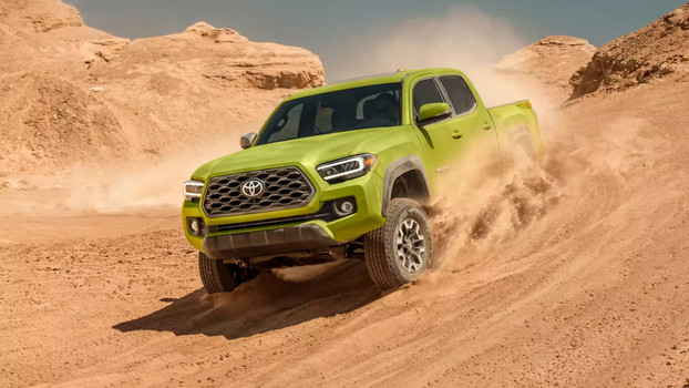 Lime green Toyota Tacoma driving through the desert on sand.